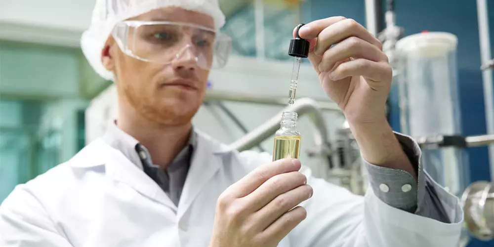 scientist testing and holding cannabis cbd oil bottle in chemical laboratory