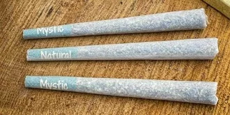 A set of three rolled hemp papers on top of a wooden table.