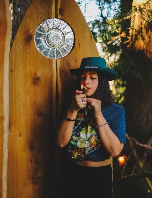 girl lighting up in front of wooden door
